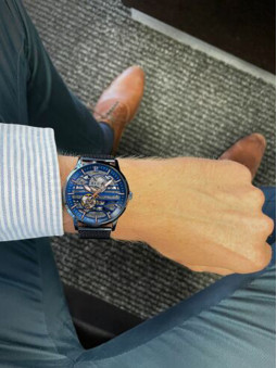 une jolie montre homme pierre lannier à son poignet, cadran squelette ajouré, bracelet milanais bleu, référence 332C469