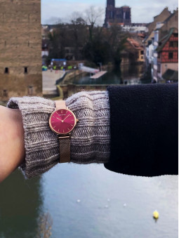 Montre Pierre Lannier en or rose référence 014J958 au poignet sur un pull gris et au fond la ville de Strasbourg